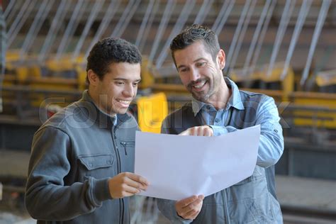 male supervisor  worker discussing  blueprints  industry