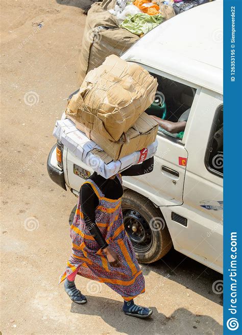 unidentified ghanaian woman carries boxes on her head at the ku stock