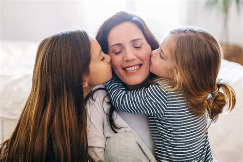 portrait of daughters kissing her mom at home by stocksy contributor