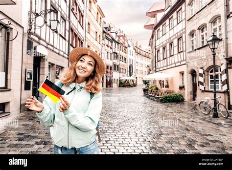 Young Asian Woman Tourist Traveling With German Flag Near The Famous