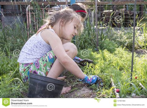 closeup image of two teenage girls weeding garden bed female gardening