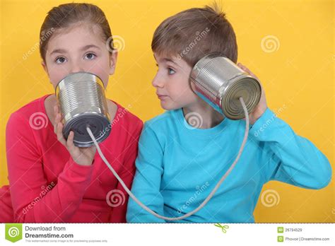 niños que usan las latas como teléfono imágenes de archivo