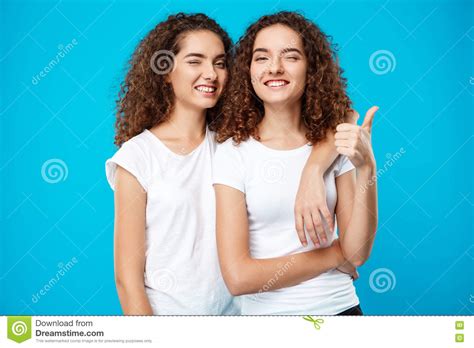 Two Girls Twins Smiling Winking Showing Like Over Blue Background