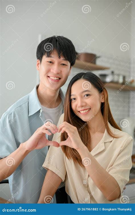 Lovely Asian Couple Making A Heart Hand Sign Together In The Kitchen