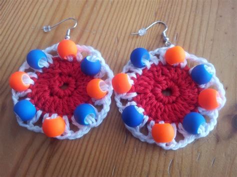 crocheted earrings  orange  blue beads   sitting   wooden surface