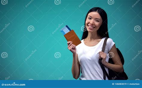 smiling woman with backpack showing passport with tickets tourism