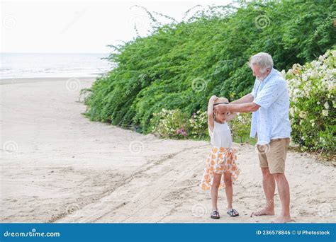 asia cute small girl and caucasian old man relaxing on the beach stock