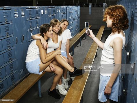 teenage girls taking picture with mobile phone in gym locker room
