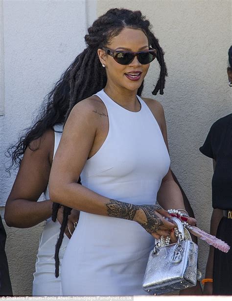 rihanna dabs her face with a tissue as she returns to barbados for