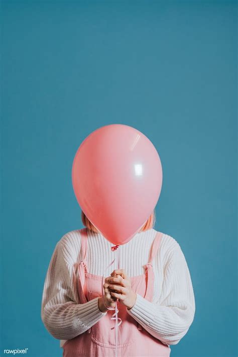 A Woman Holding A Pink Balloon In Front Of Her Face