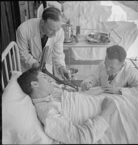 a male nurse assists a doctor as he gives a patient an injection at