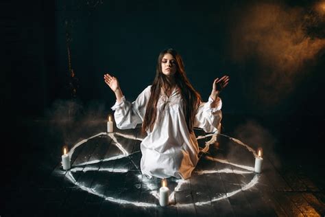 heks  wit overhemd zittend  het midden van pentagram cirkel met kaarsen occult ritueel