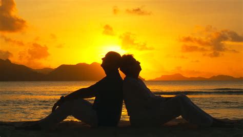 romantic teen couple kissing on the beach at sunset stock