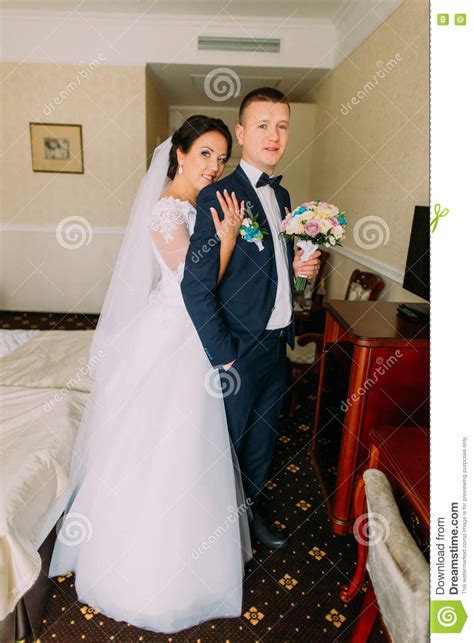 Gorgeous Bride And Elegant Groom Posing In Hotel Room After Wedding
