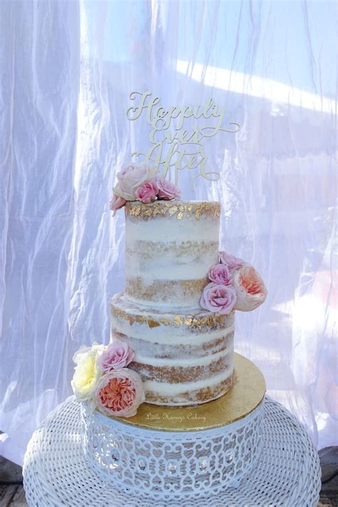 naked wedding cake with gold leaf and fresh flowers