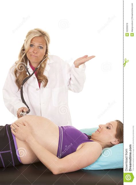 Woman Doctor Listening To Belly Of Pregnant Woman Stock
