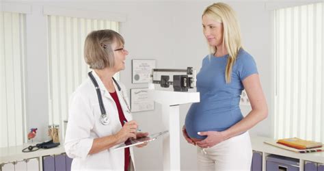 pregnant woman standing on scale in doctor s office stock