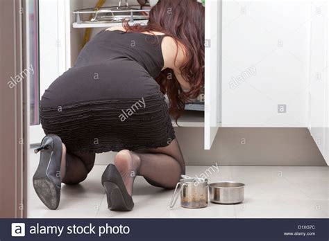 Woman Bent Over In The Kitchen Looks In A Cabinet