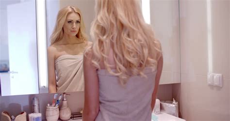 beauty teenage girl in red dress applying make up and admiring herself in the mirror beautiful