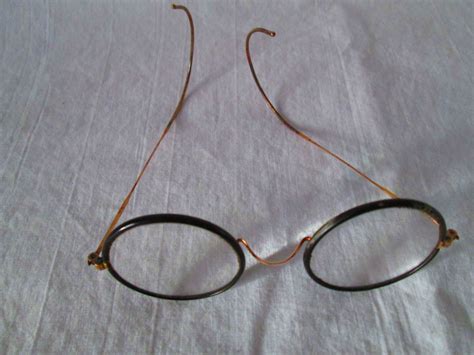 pair of wire rim eye glasses with black bakelite around lenses early
