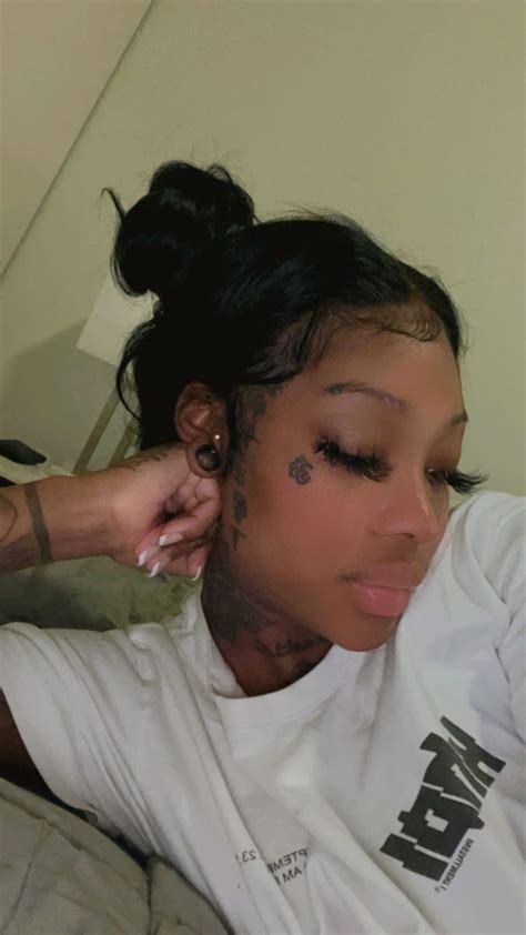 A Woman With Tattoos On Her Face Laying Down