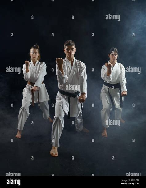 Male And Female Karate Fighters In White Kimono Group Training Dark