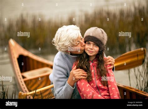 portrait of grandmother kissing her granddaughter on the cheek stock