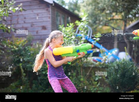 mädchen squirting wasserpistole im garten stockfotografie alamy