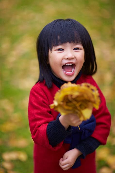 Happy Little Asian Girl Holding Gingko Leaf Smile By Stocksy