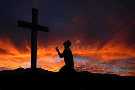 silueta del hombre que ruega a una cruz con el cloudscape