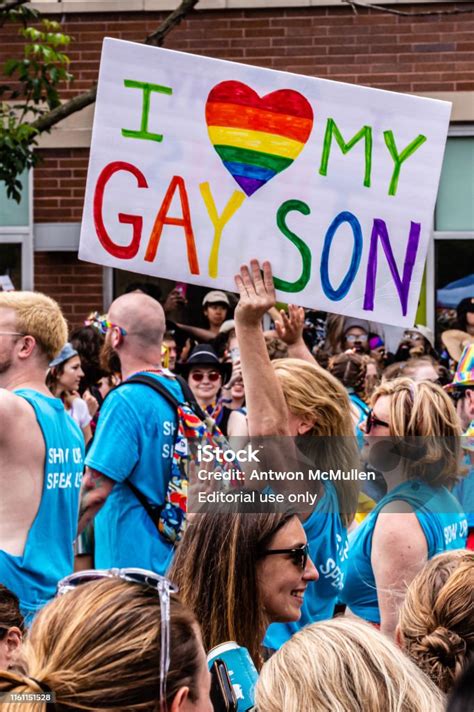 a mother carries a sign that reads i heart my gay son while marching in