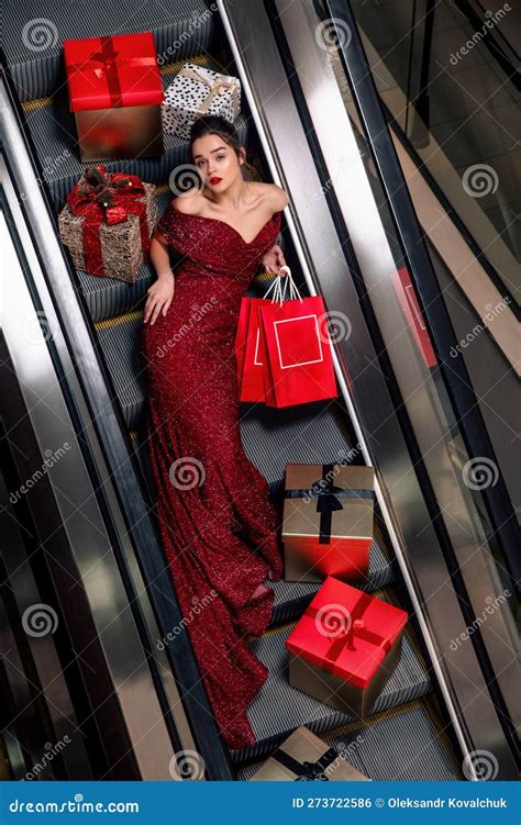 Woman In The Red Shiny Dress Lying On The Escalator Between The Red