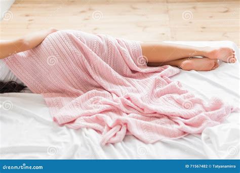 woman covered  pink blanket lying  bed sideview stock photo