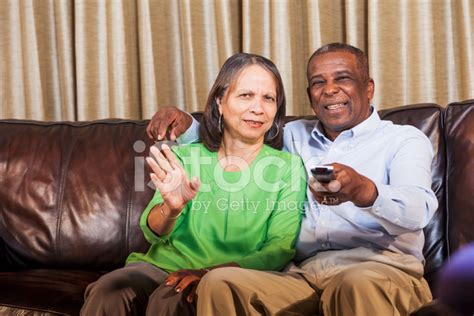 senior african american couple watching tv on couch stock