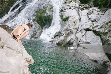 a woman contemplating jumping into a swimming hole in the woods with a