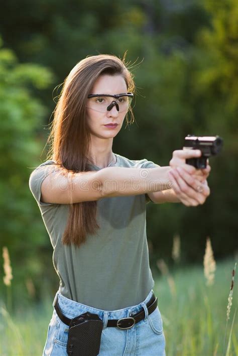 girl shooting instructor with a gun in his hand aiming at the target