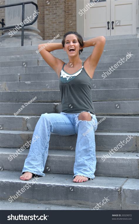 Barefoot With Knee Peeking Out Of A Pair Of Worn Jeans