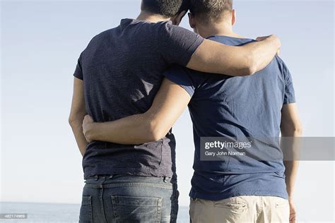 cropped shot of mature male couple with arms around each other at coast