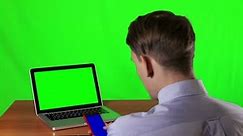 man uses a smartphone with a blue screen with a laptop with green screen.horizontal. With a green screen background.chroma key