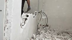 construction worker with a big sledgehammer hits the concrete wall.