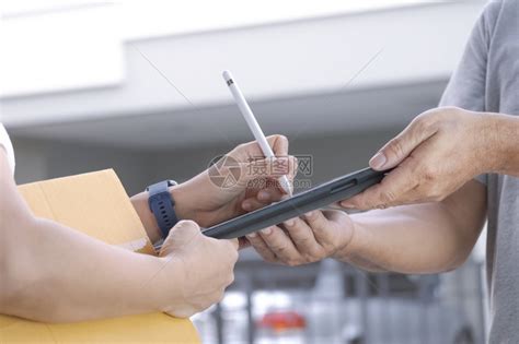 妇女用电子笔在平板屏幕上签字时从家中送货员那里获得在线产品后用电子笔签名的手无线盒子交货高清图片下载-正版图片307807618-摄图网