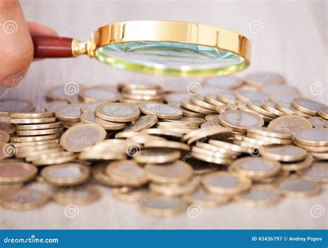 Businessman Examining Heap of Coins through Magnifying Glass Stock ...