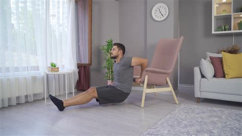 Young man doing triceps dips on the couch. Young man doing triceps at ...