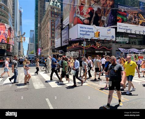 A crowd of people cross the street in the heart of New York City Times ...