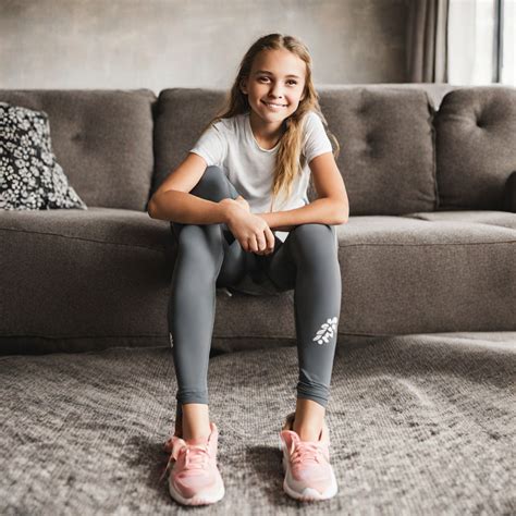 Tween girl wearing athletic leggings sitting on sofa by Bob Brandon ...