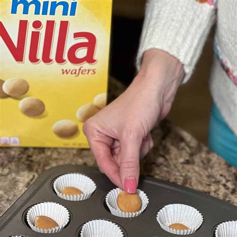 placing Nilla wafers into a muffin pan lined with cupcake liners ...