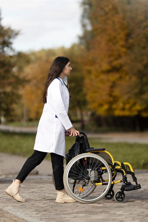 Premium Photo | Cute young nurse is carrying a wheelchair outdoors a ...