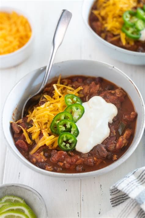 A bowl of Laura's quick slow cooker turkey chili, topped with shredded cheese, sliced green onions,