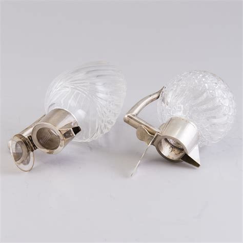 Two glass carafes with hinged silver lids and silver handles, K ...