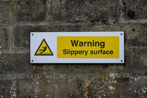 Yellow Warning Sign Saying Slippery Surface Stock Image - Image of wall, signage: 332577795